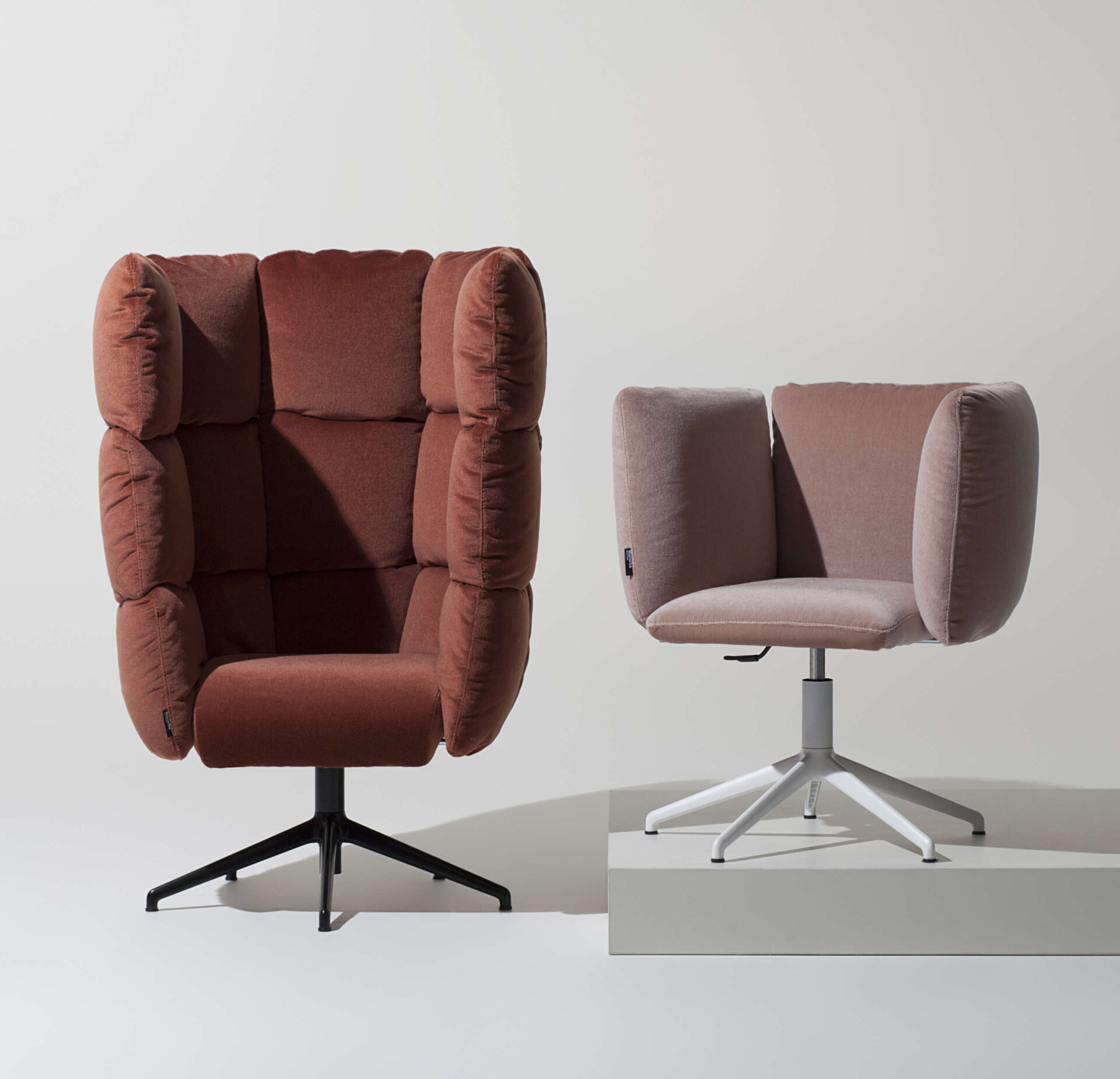 A small medium swivel armchair and a slim swivel armchair inside an open space