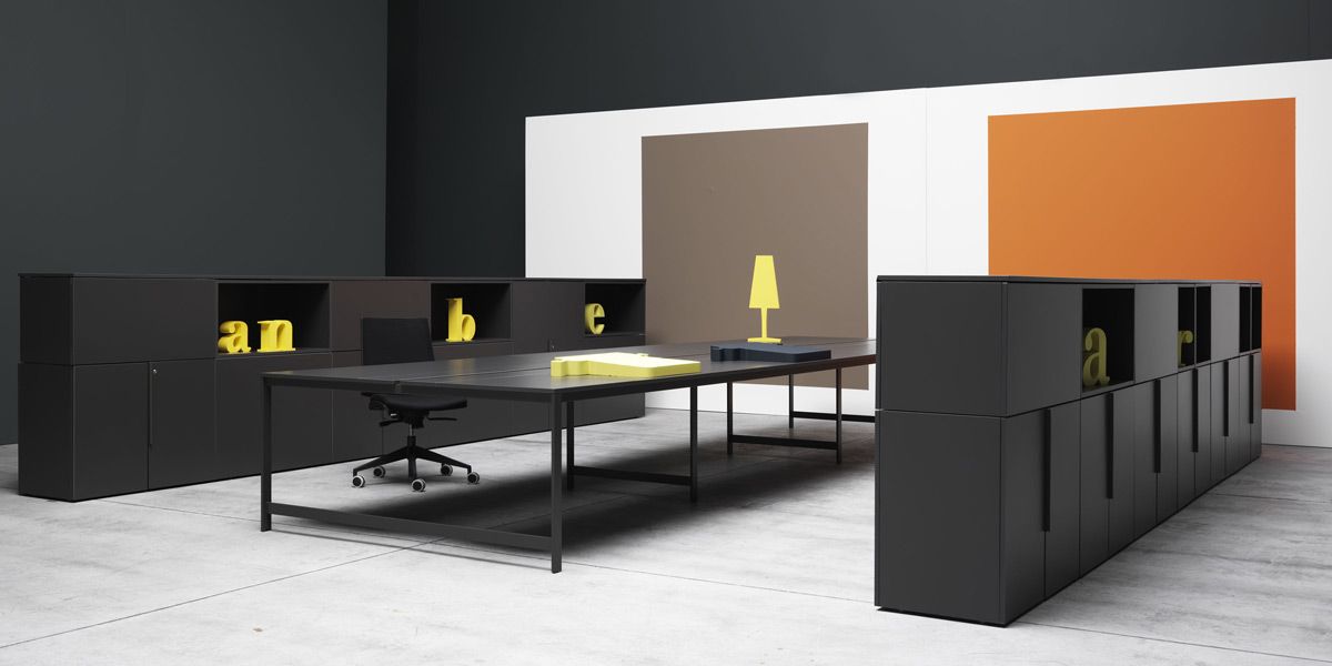 Foto di un open space con due pareti divisorie nere collezione K-Box e un tavolo al centro