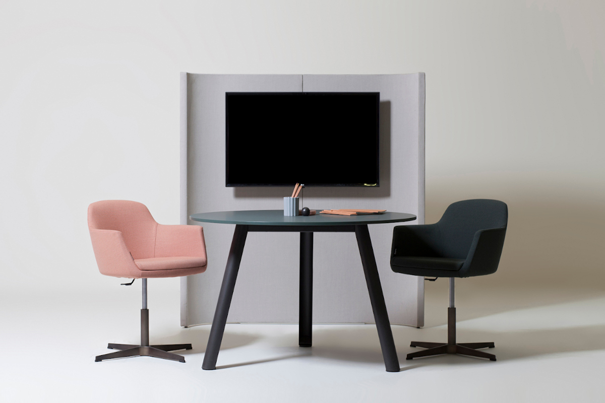Un tavolo rotondo Apollo tra due sedute Vogue e il portamonitor della collezione Undecided